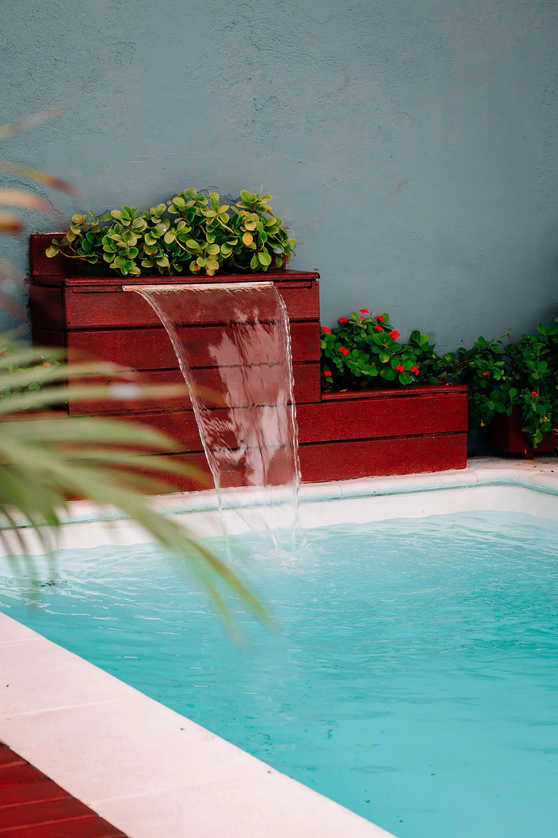 Pool with waterfall feature and greenery.